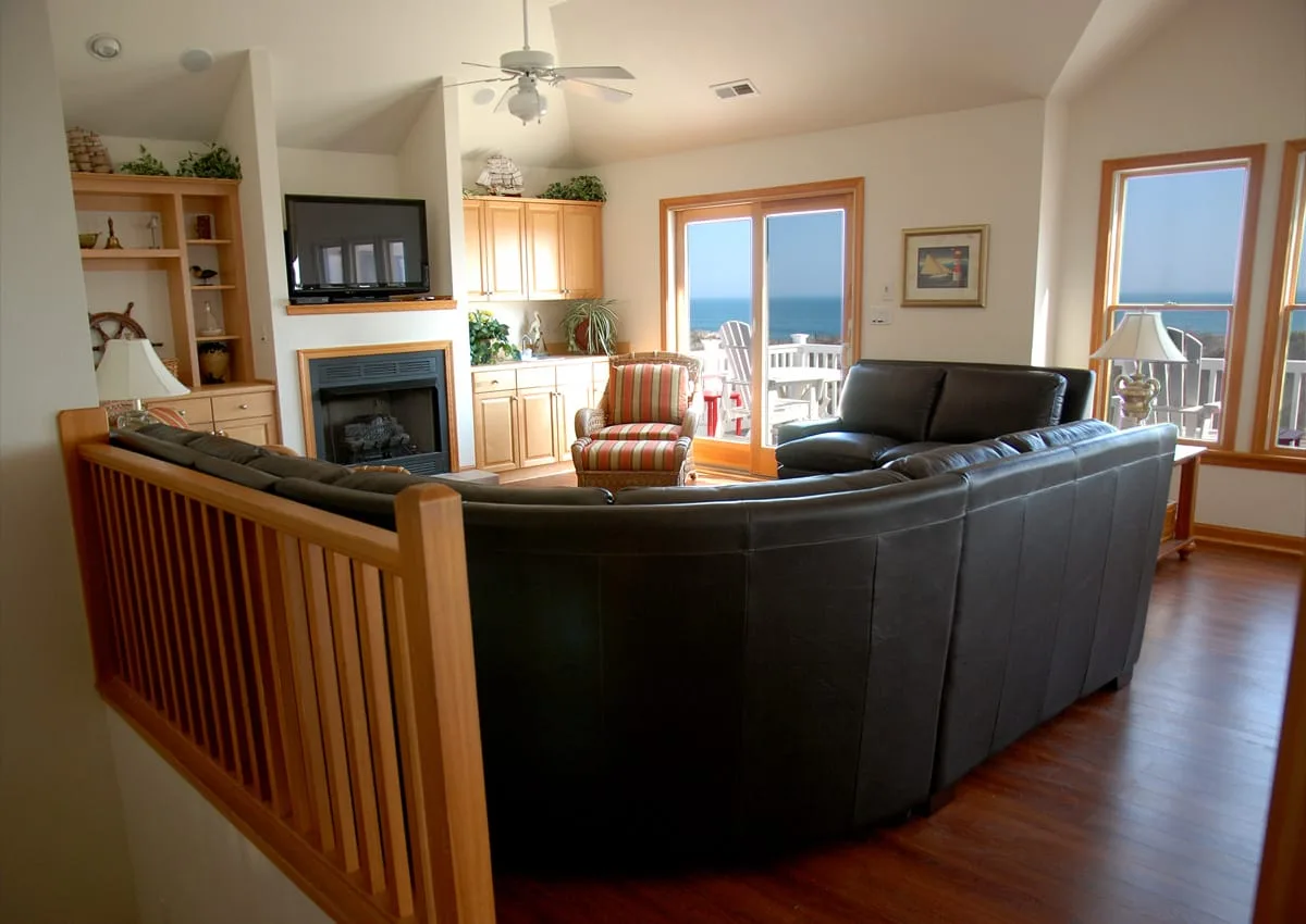 Una sala de estar con asientos curvos, una chimenea y ventanas con vista al agua.
