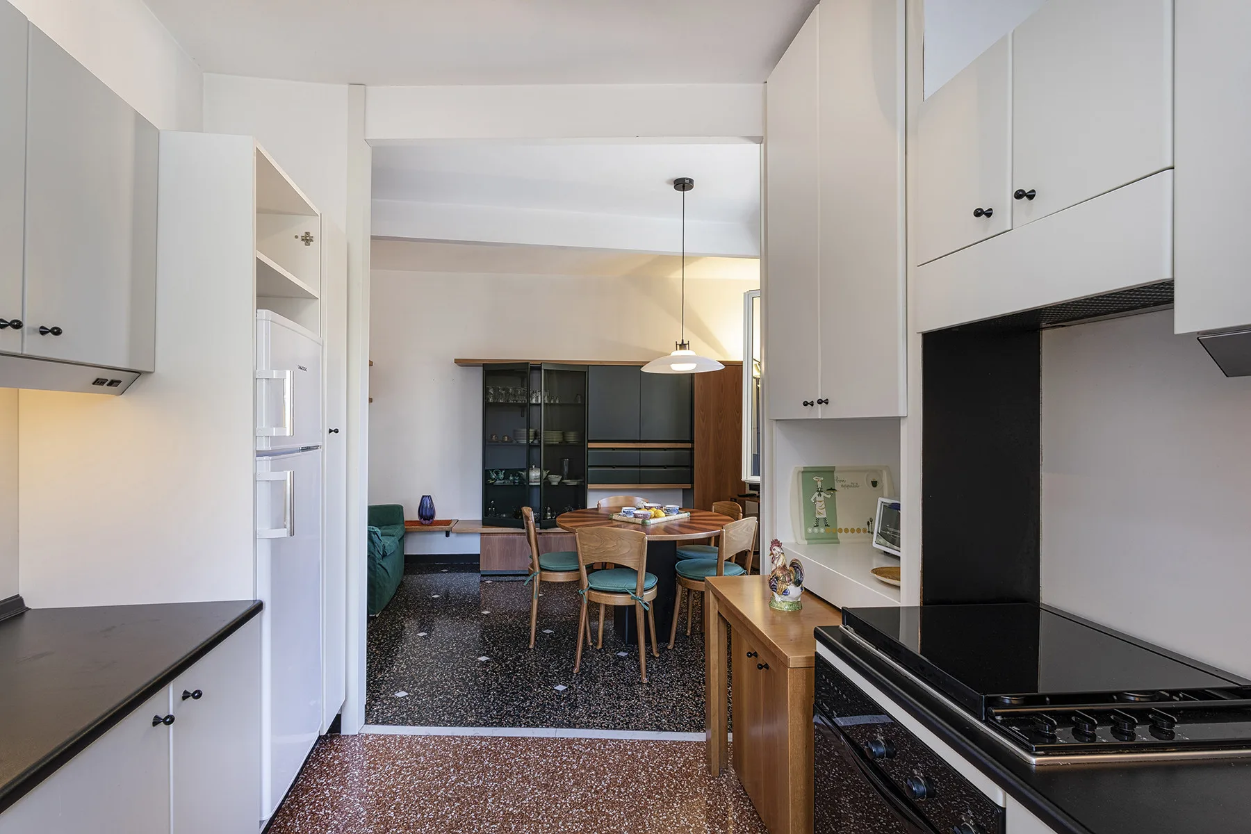 A bright kitchen opens onto a dining area with a table and chairs.
