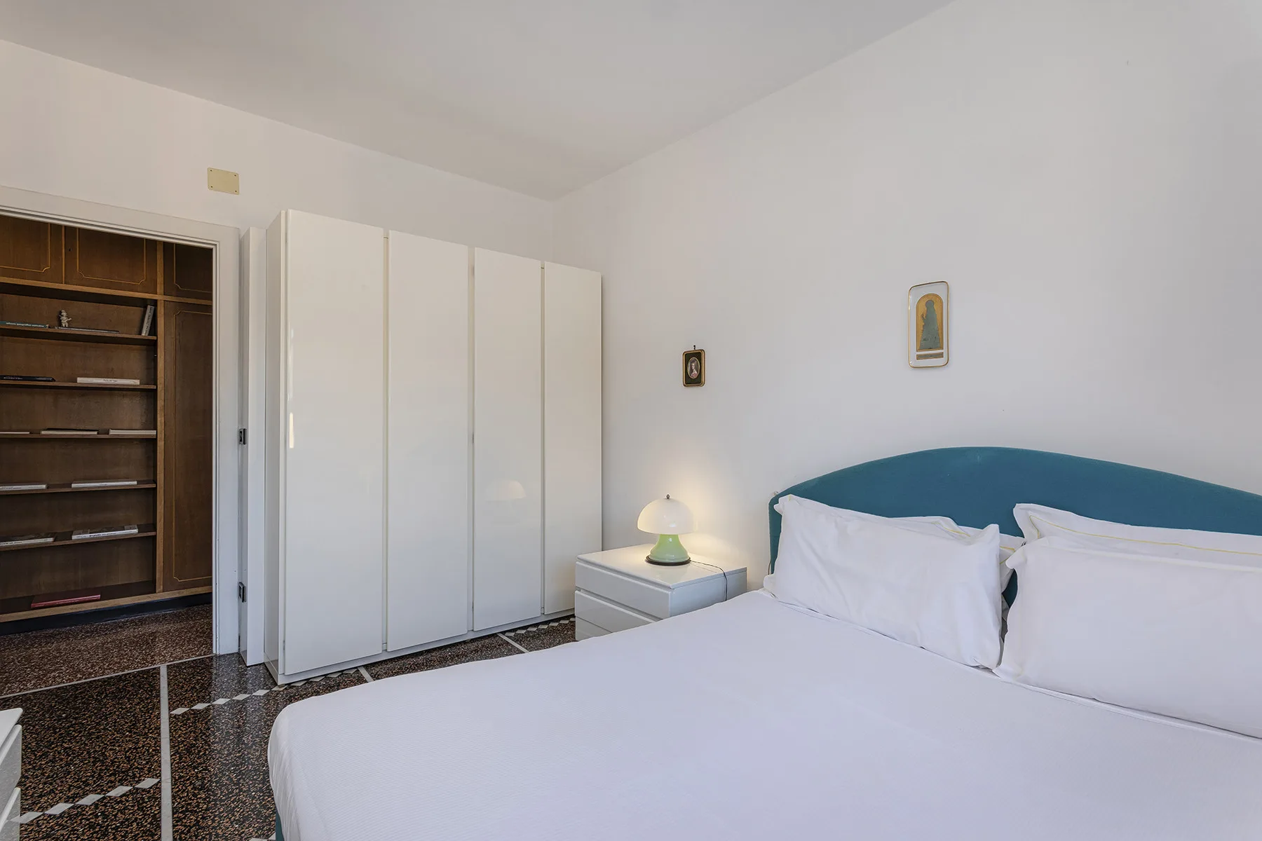A bedroom with a large bed, white wardrobes, and a bedside lamp.