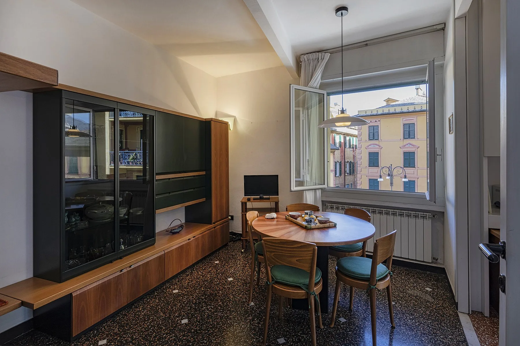 A dining area with a round table and a large open window.