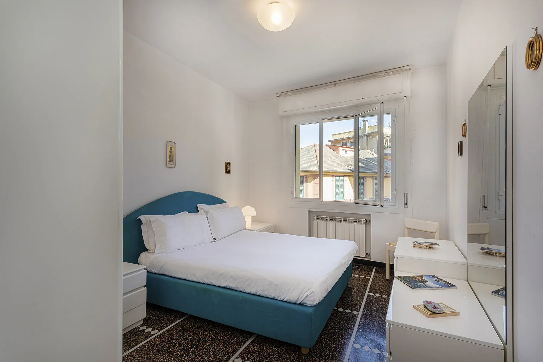 A bright bedroom with a bed beside a large window.