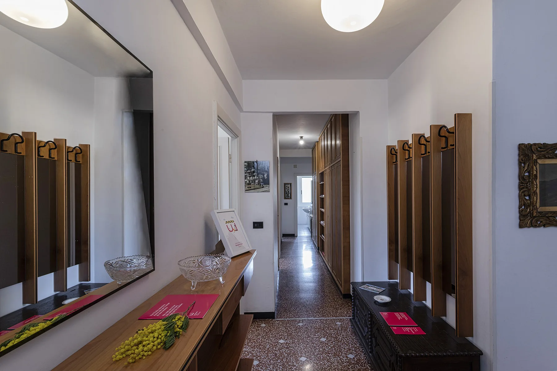 A narrow hallway has a long counter and wall-mounted coat hooks.
