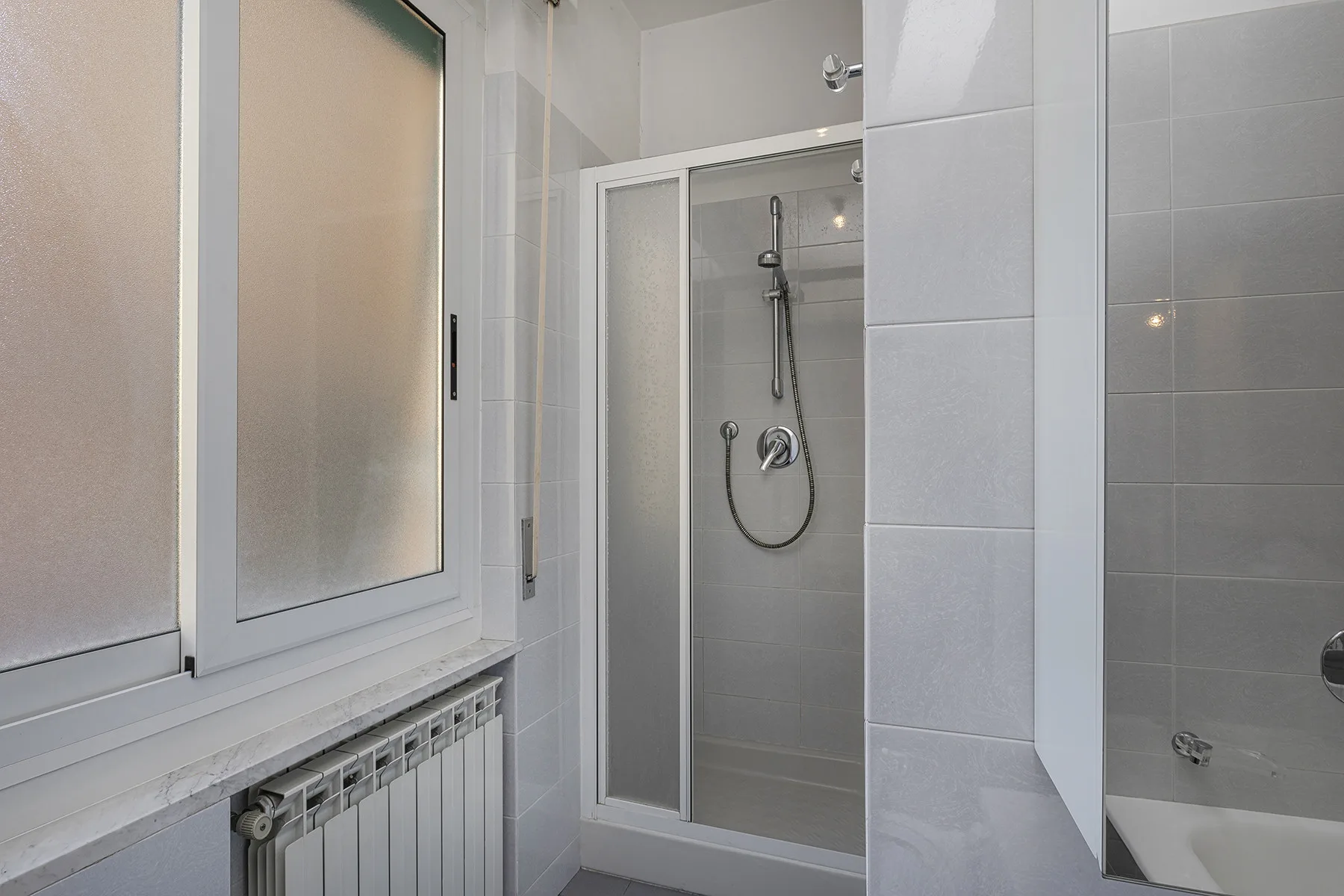 A tiled bathroom with a shower and frosted-glass window.