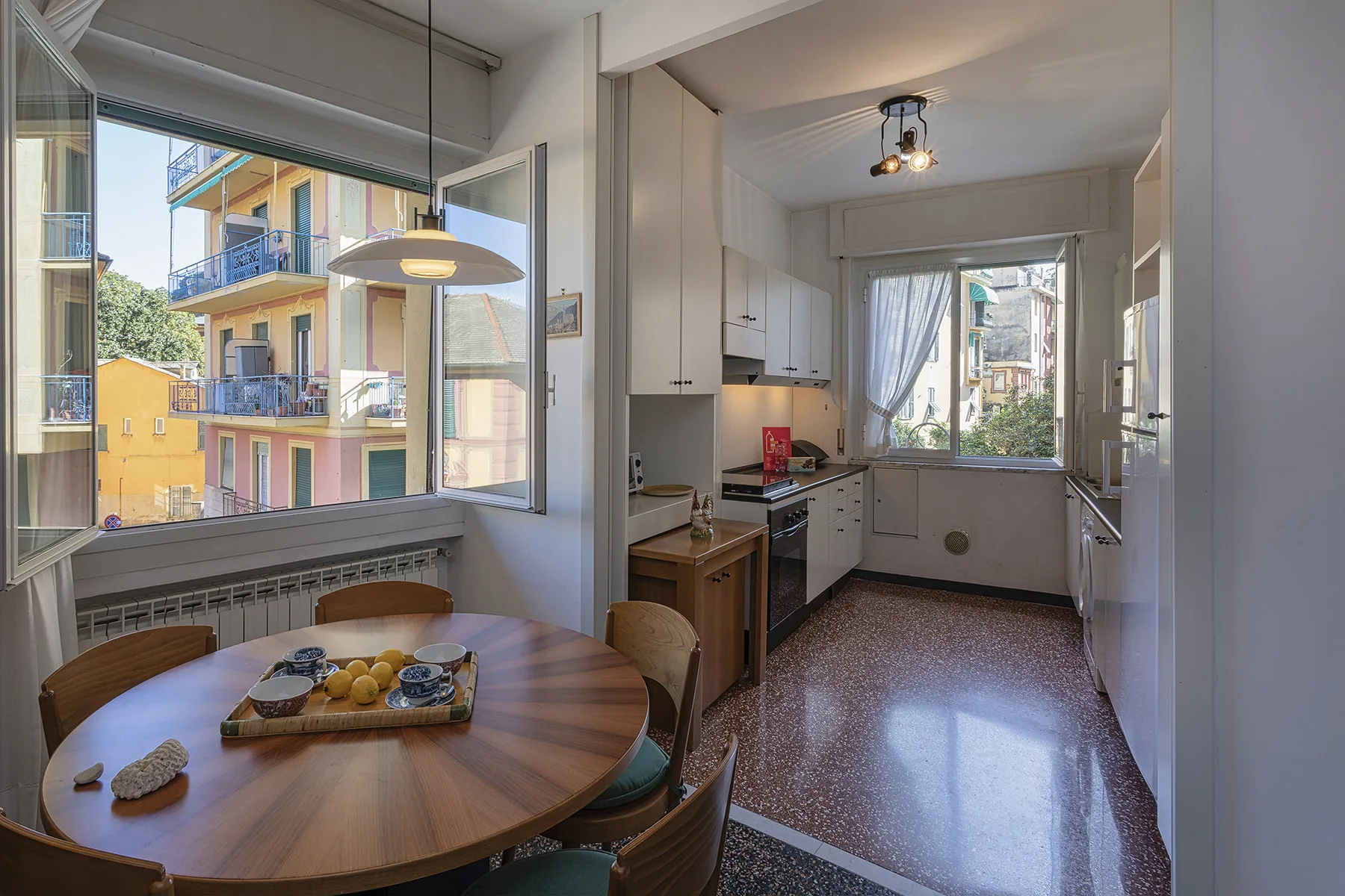 A bright kitchen and dining area with a round table beside large windows.