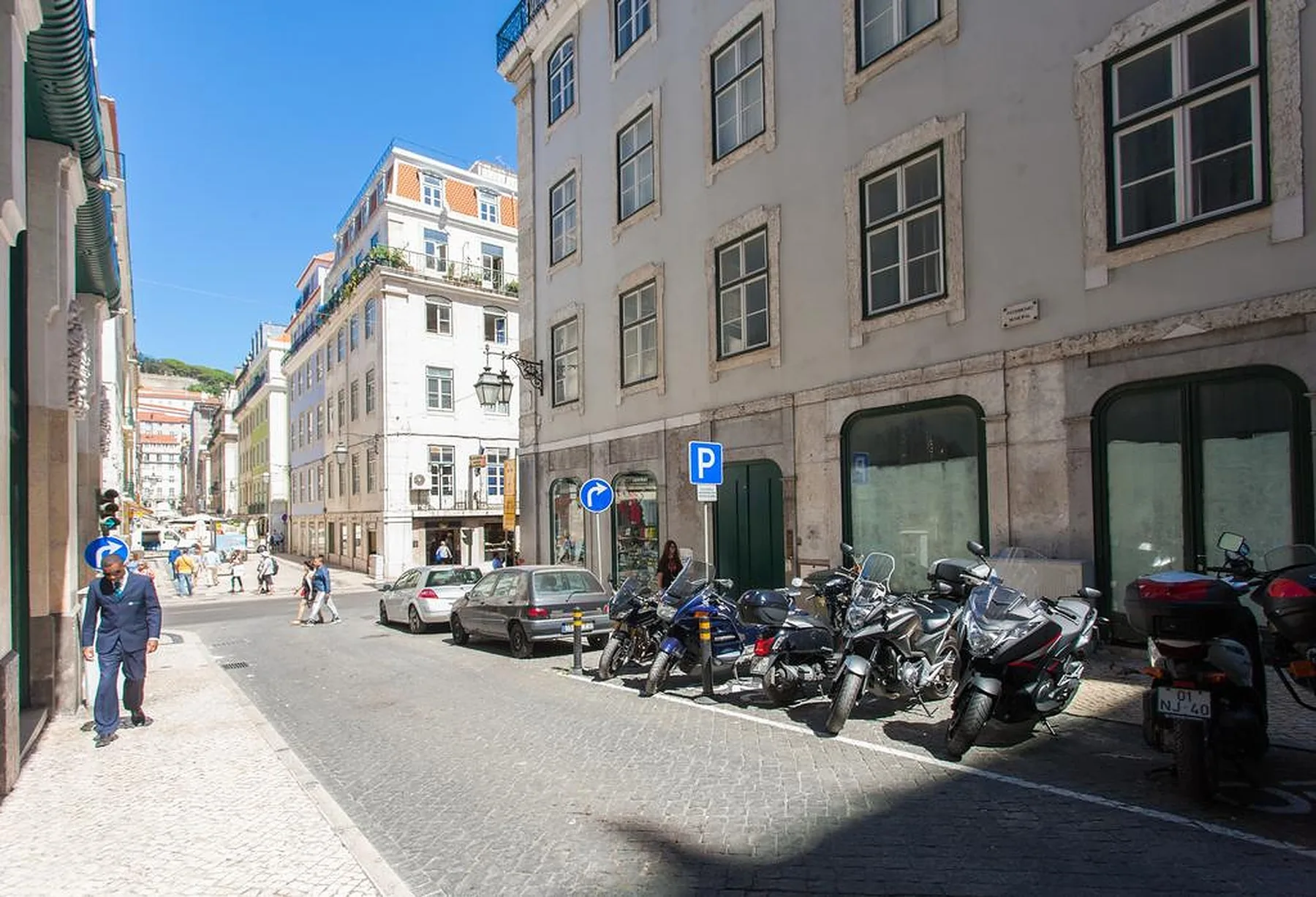 Una calle adoquinada de la ciudad, flanqueada por edificios y motos estacionadas.