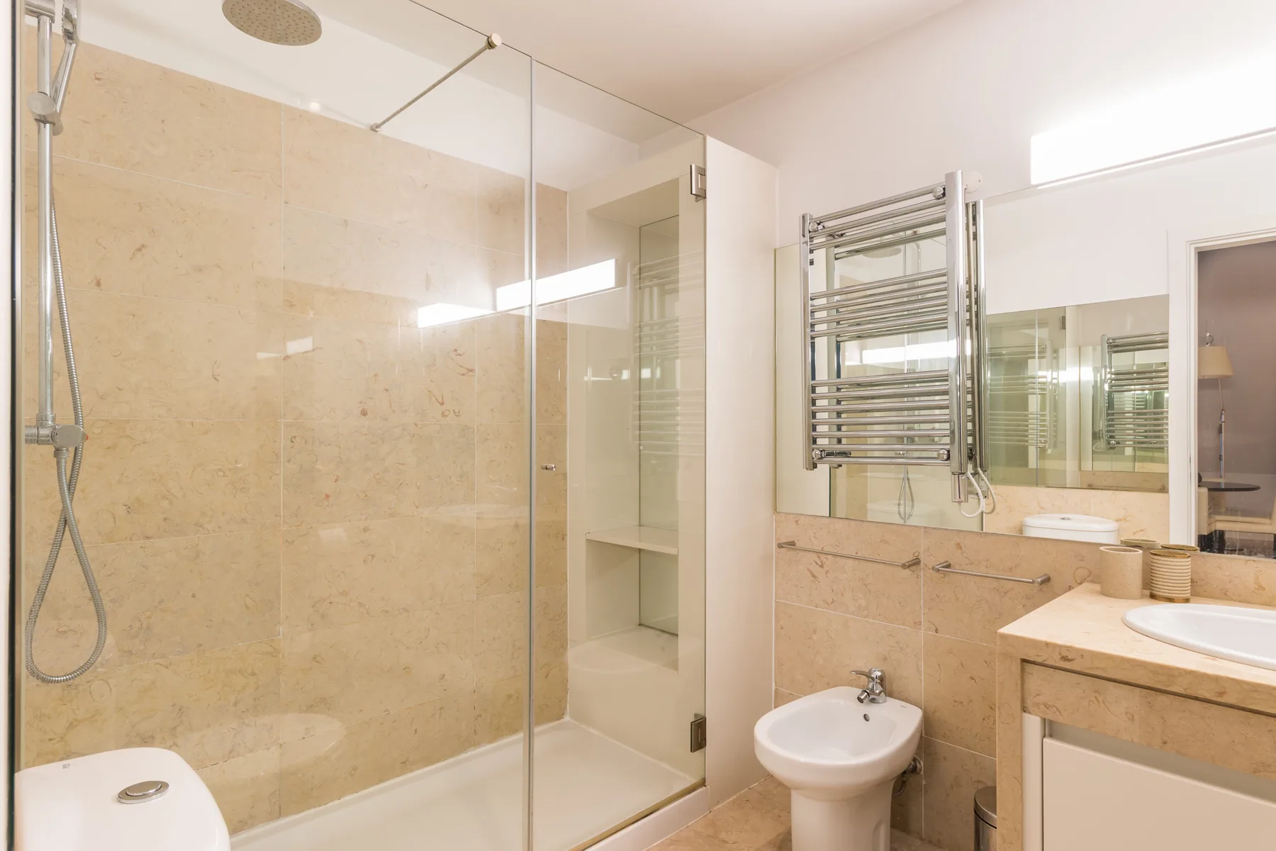 Baño alicatado con ducha de vidrio, lavabo y toallero calefactable.