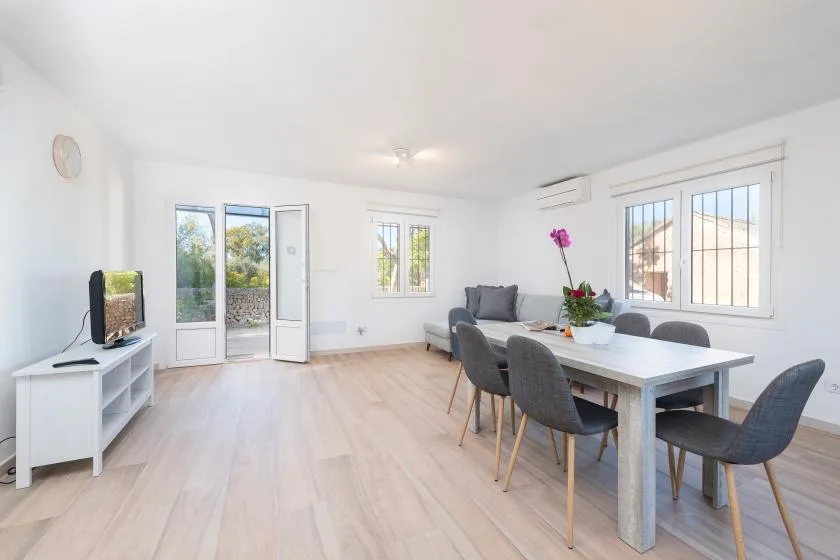Un comedor y sala luminosos con una mesa junto a grandes ventanas.