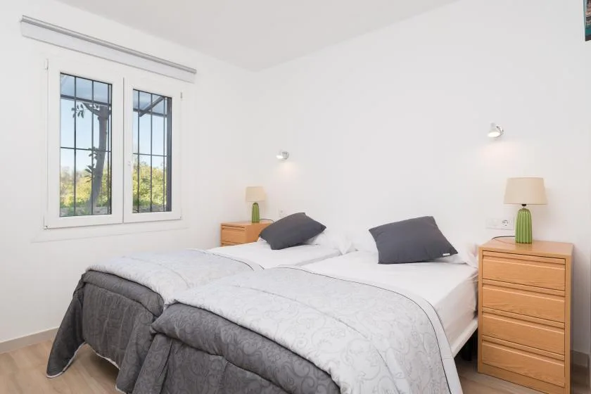 Un dormitorio luminoso con una cama grande y una ventana con vistas a la vegetación.