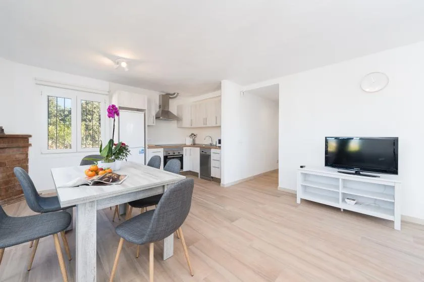 Una luminosa zona abierta de comedor y cocina tiene una mesa junto a las ventanas.