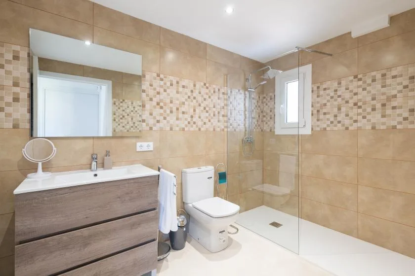 Un baño alicatado con lavabo, inodoro y ducha de cristal.