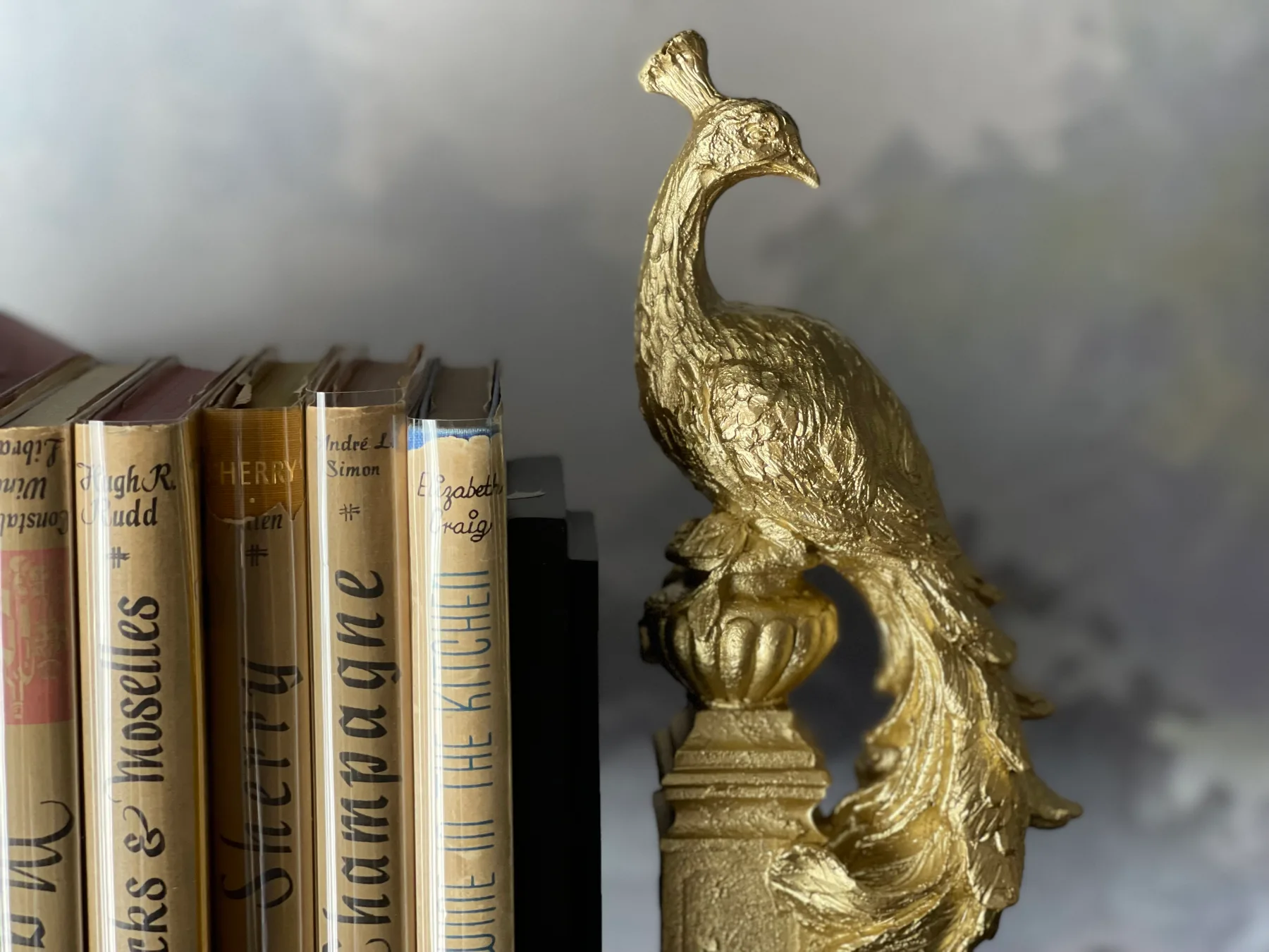 Una figura dorada de un ave está junto a una fila de libros.