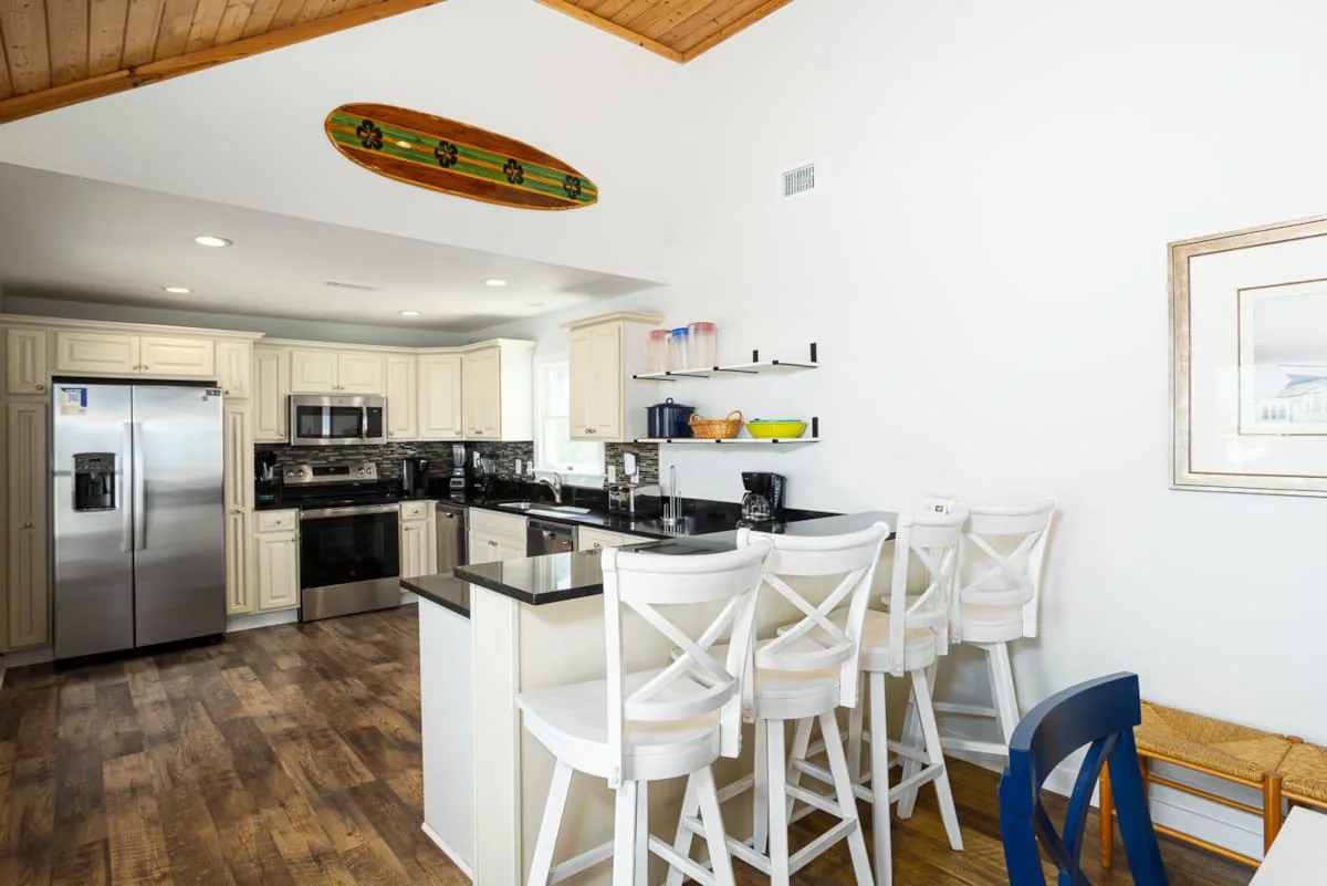 A bright kitchen with a central island, bar seating, and stainless steel appliances.