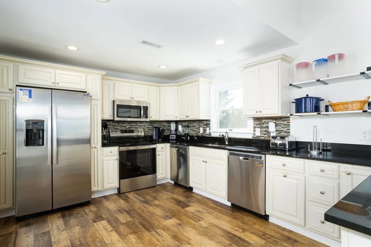 A bright kitchen with white cabinetry, stainless steel appliances, and dark countertops.