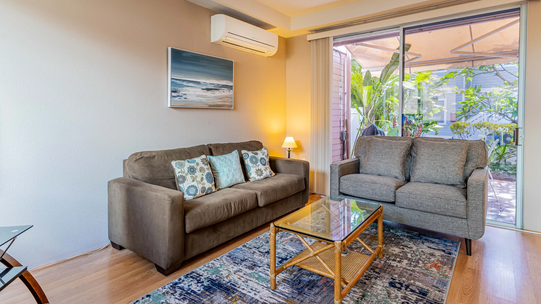 A living room with seating around a glass coffee table and a large sliding glass door.