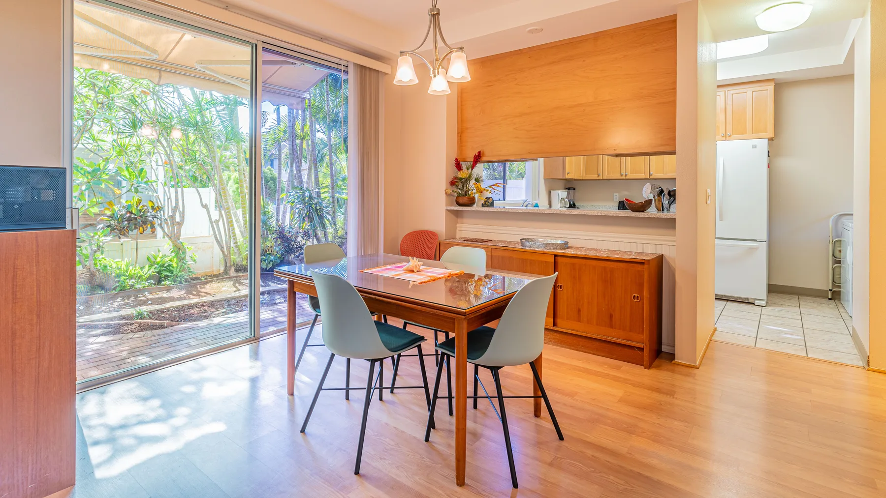 A dining area with a wooden table beside large glass doors opening onto a garden.