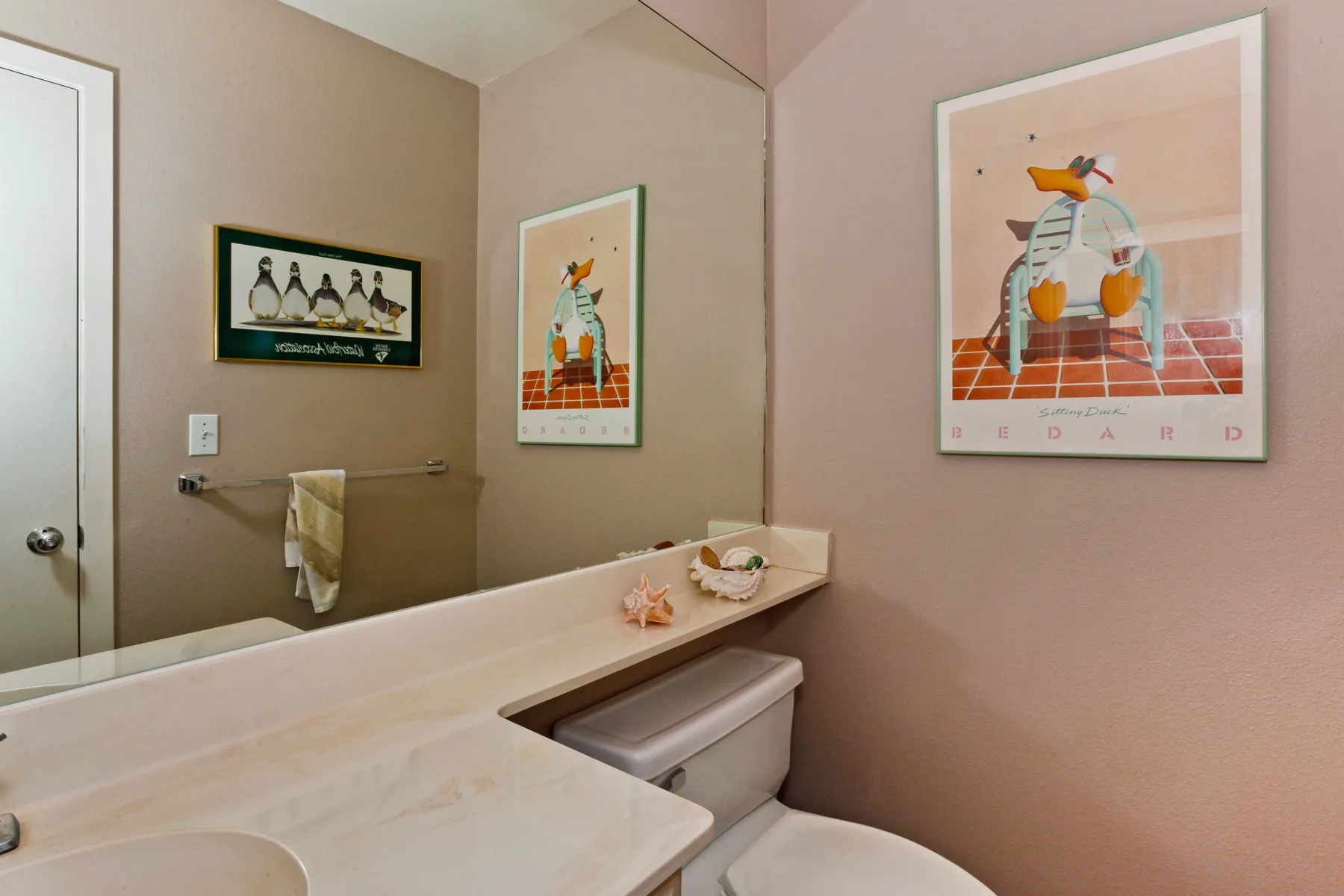 A bathroom with a wide vanity and framed artwork on the walls.