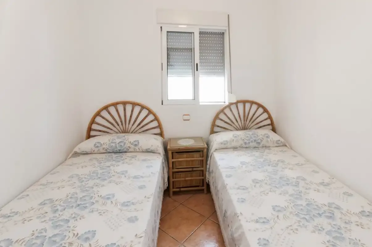 A bedroom with two single beds and a window between them.