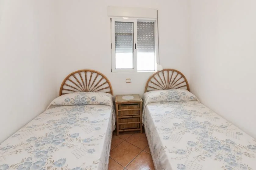 A bedroom with two single beds and a small wooden nightstand.
