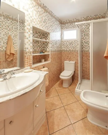 A tiled bathroom with a sink, toilet, and shower.
