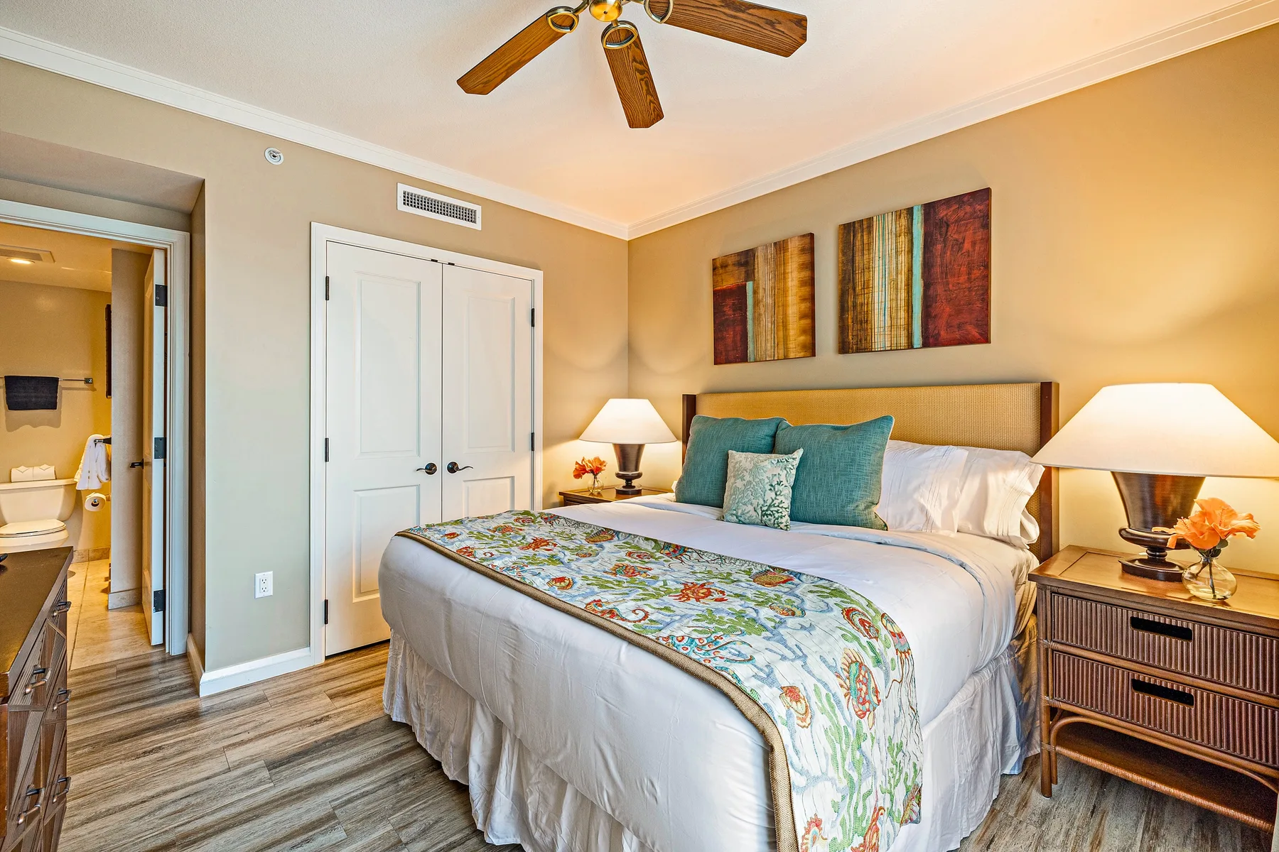 Dormitorio con una cama grande, almohadas color turquesa y lámparas de noche.