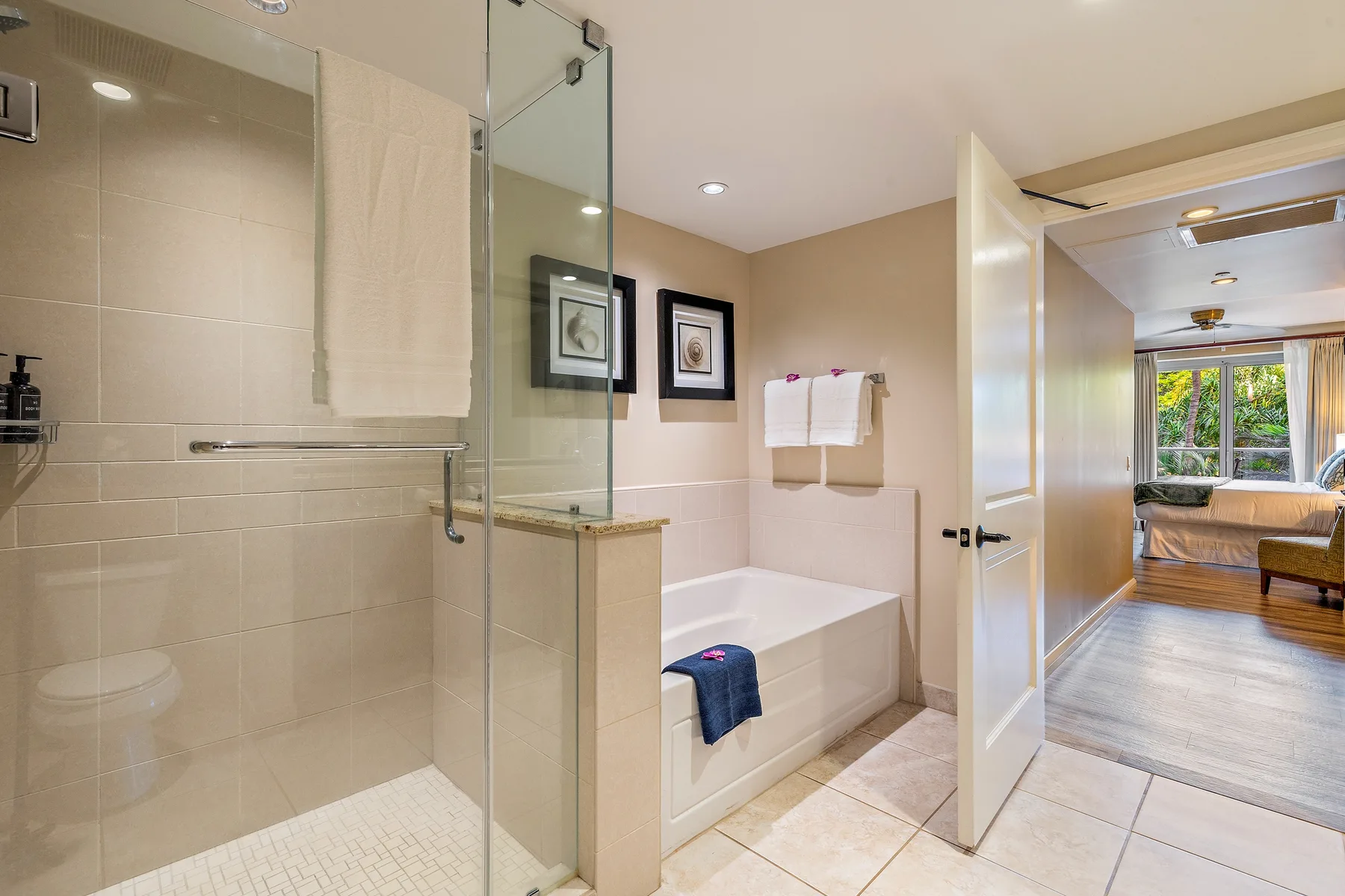 Un baño con ducha de vidrio y bañera junto a una puerta abierta.