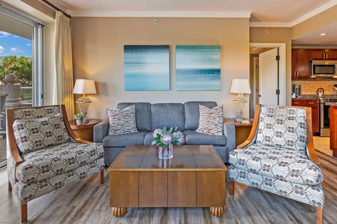 Una sala de estar con un sofá y dos sillones estampados alrededor de una mesa de centro de madera.