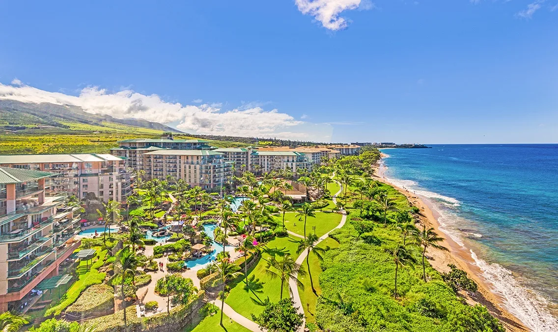 Un complejo junto a la costa bordea jardines y una línea de playa curva.