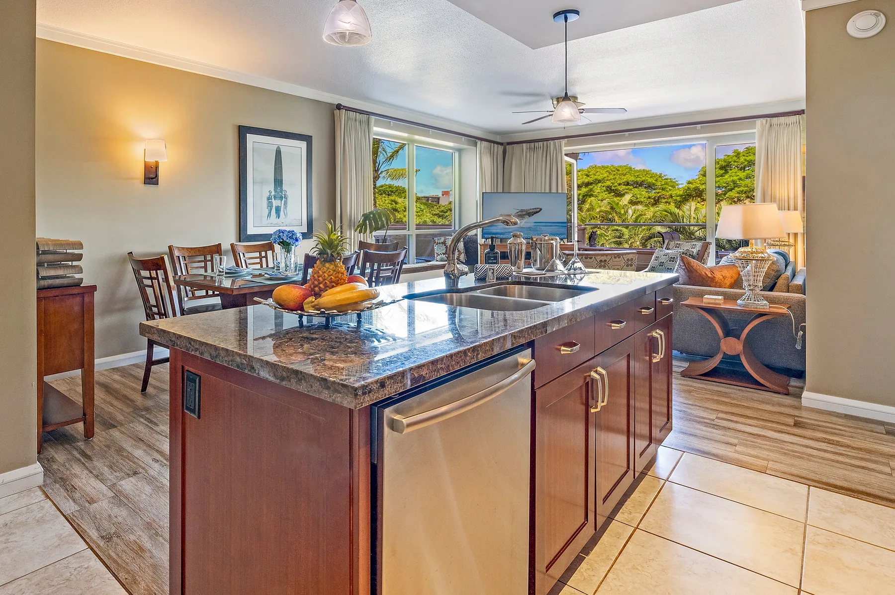 Una cocina abierta con comedor tiene una isla grande y amplias ventanas con vistas a la vegetación.