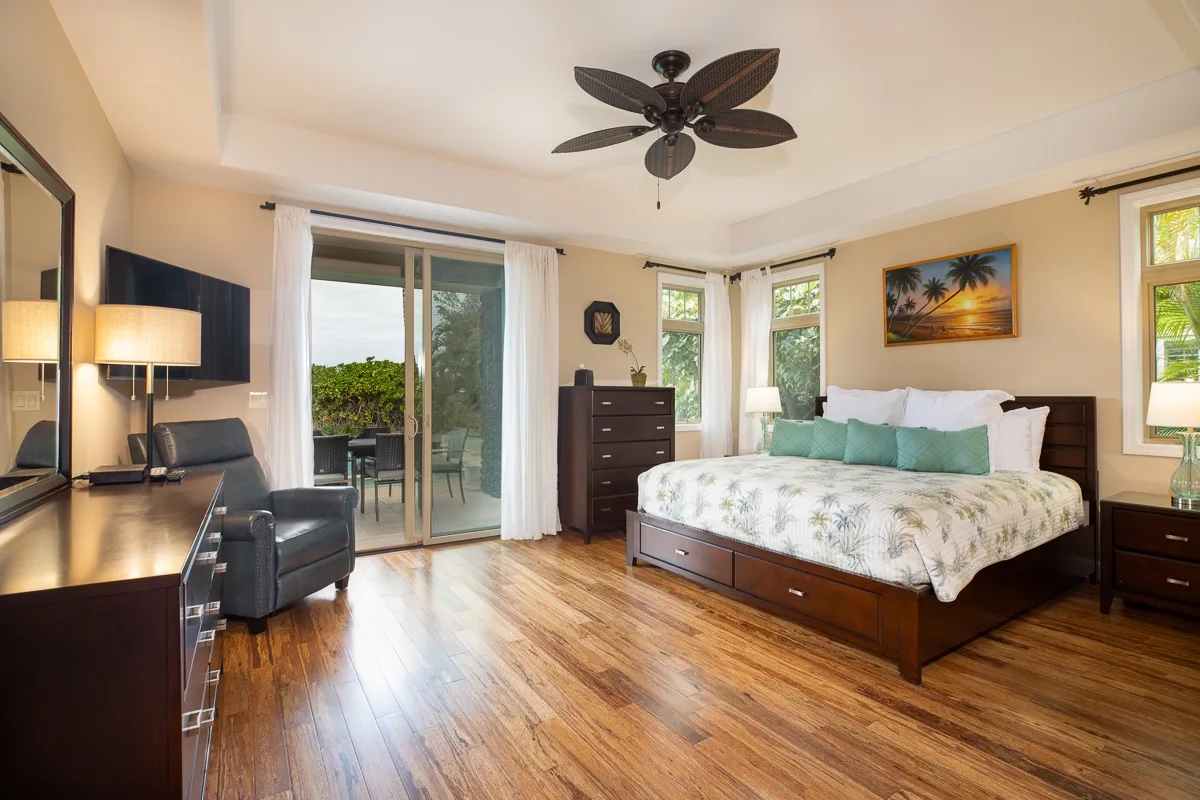 A bedroom with a large bed, dark wood furnishings, and sliding glass doors.