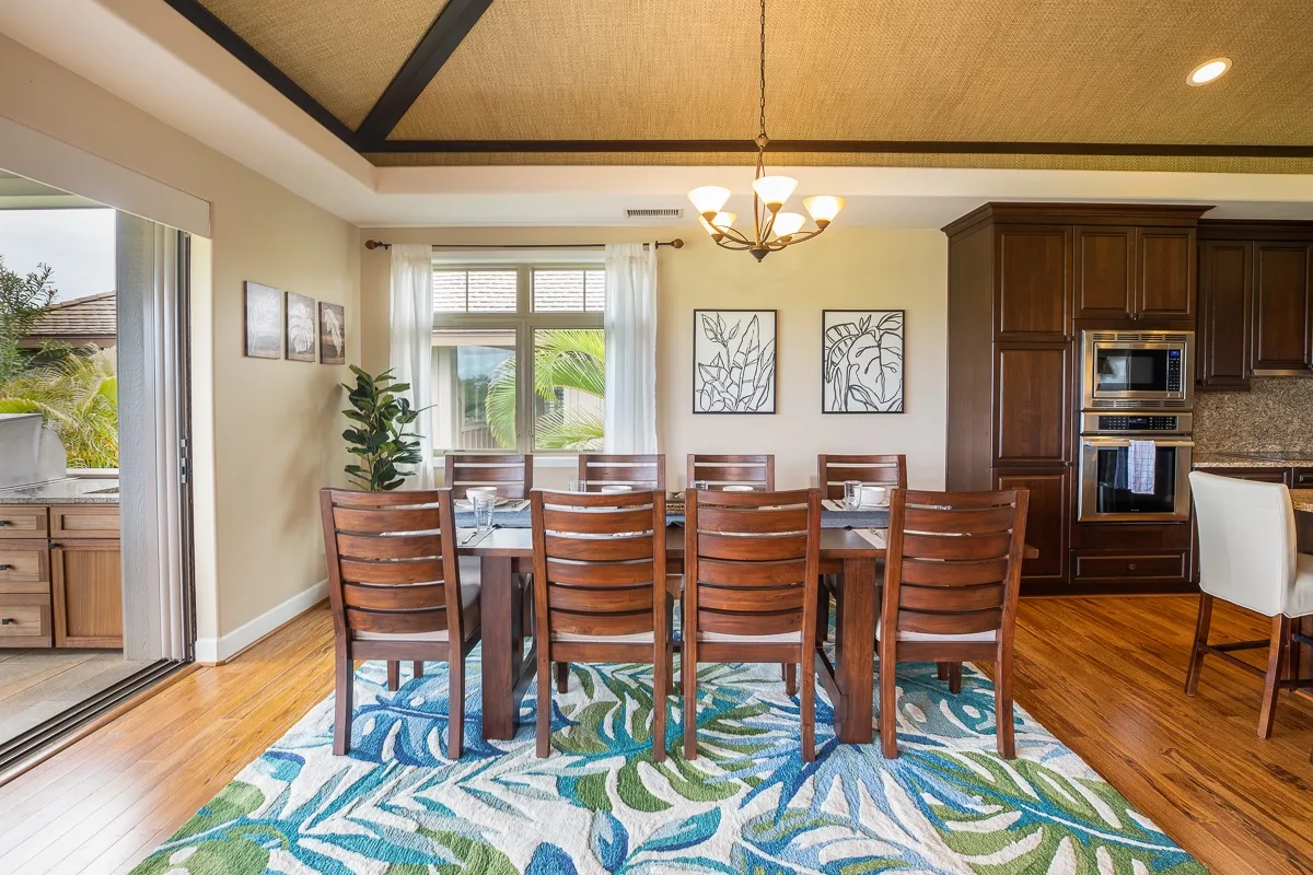 A dining area with a wooden table and chairs on a patterned rug.