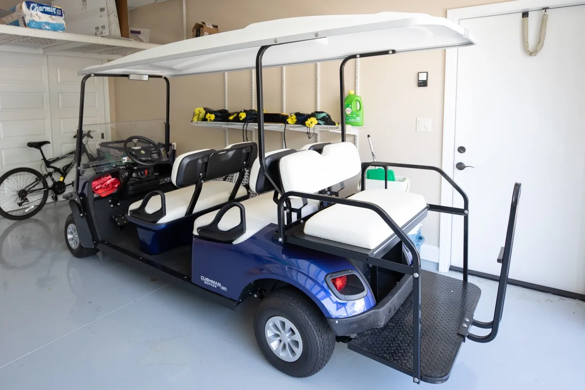 A golf cart is parked in a garage beside a white door.
