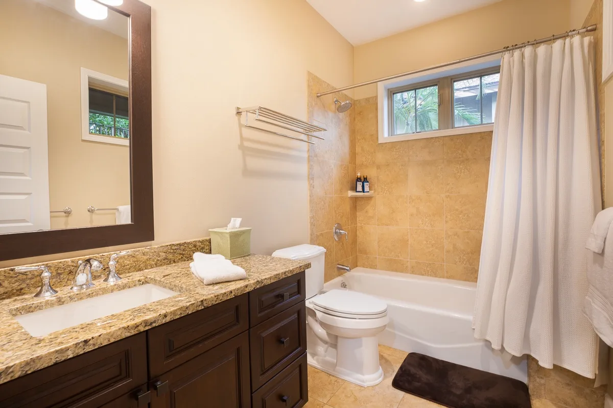 A bathroom with a vanity, toilet, and bathtub behind a shower curtain.