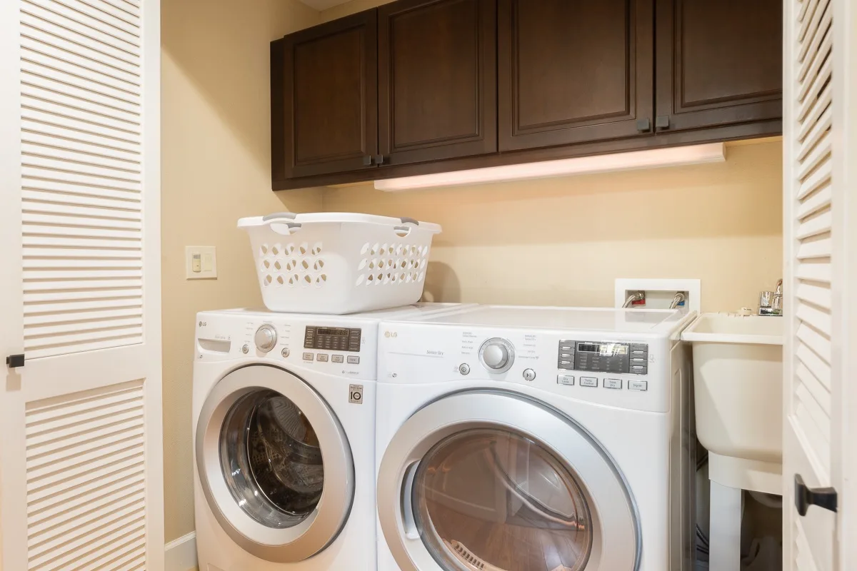 Laundry room with front-loading washers and dark cabinets above.