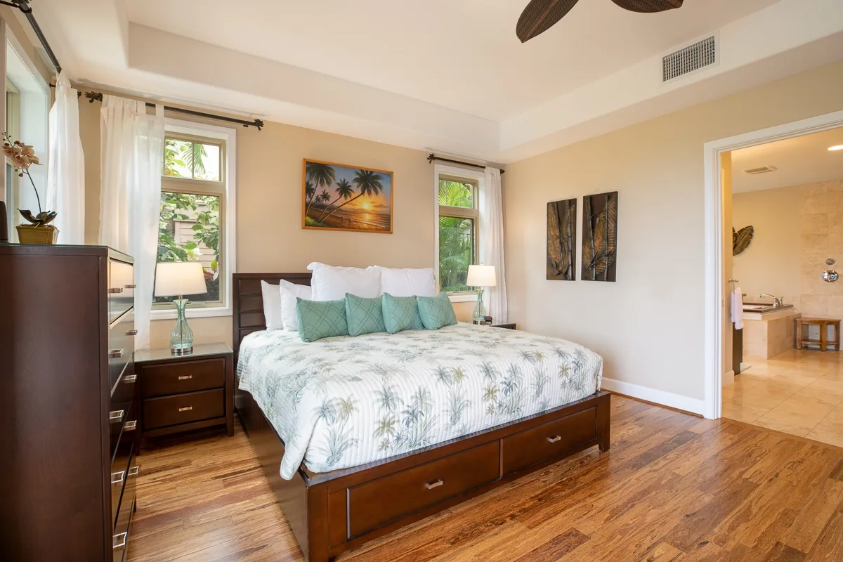 A bright bedroom with a bed, bedside tables, and windows.