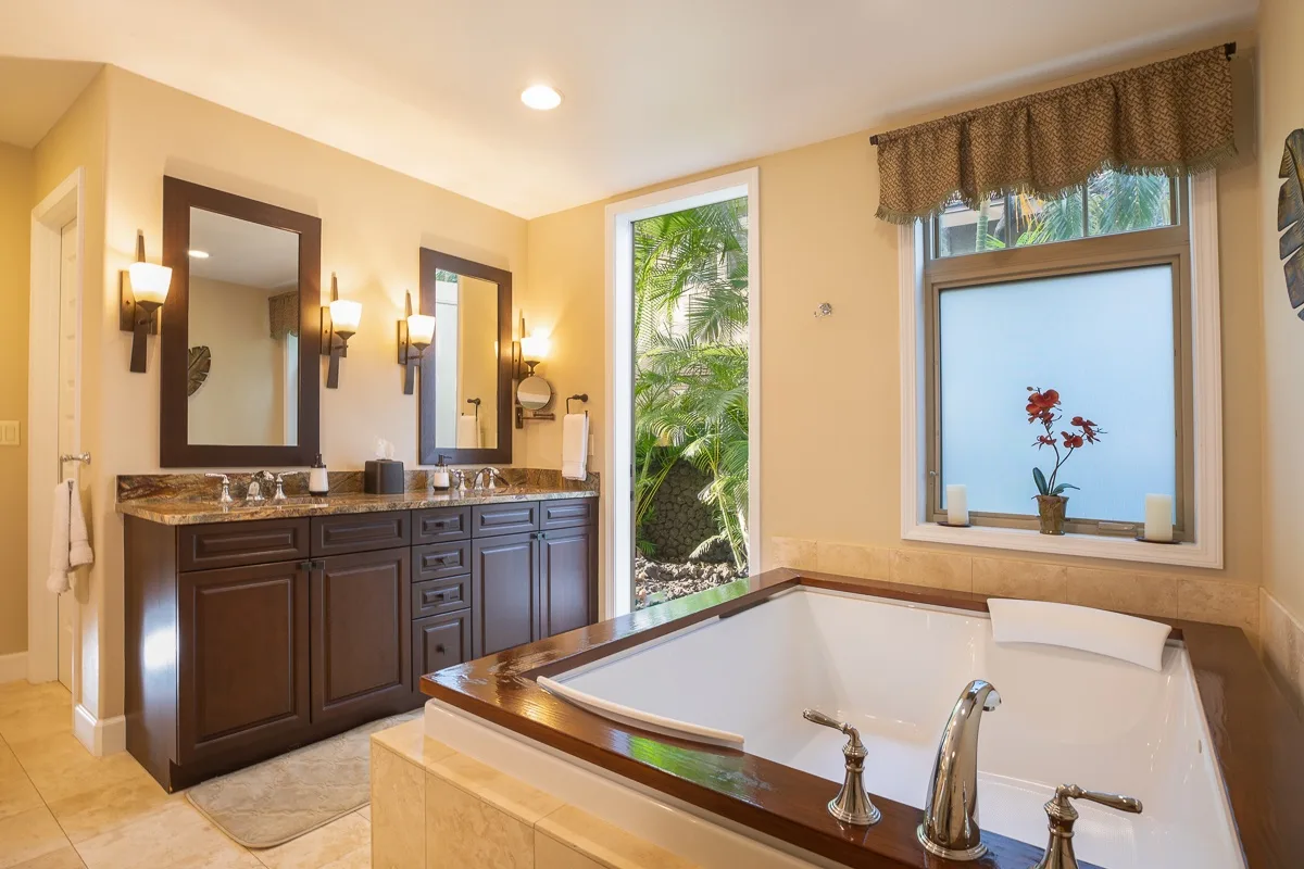 A bathroom with a large bathtub and a dark wood vanity.
