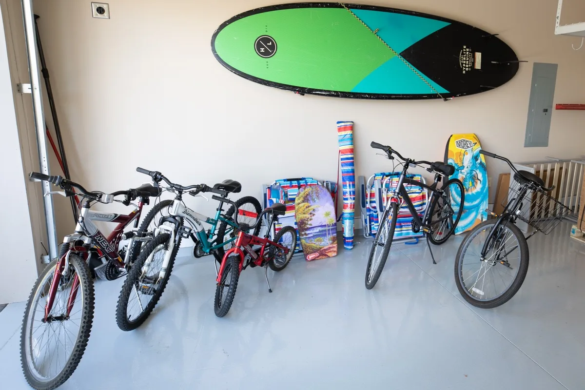 A garage with several bicycles and colorful boards stored along the wall.