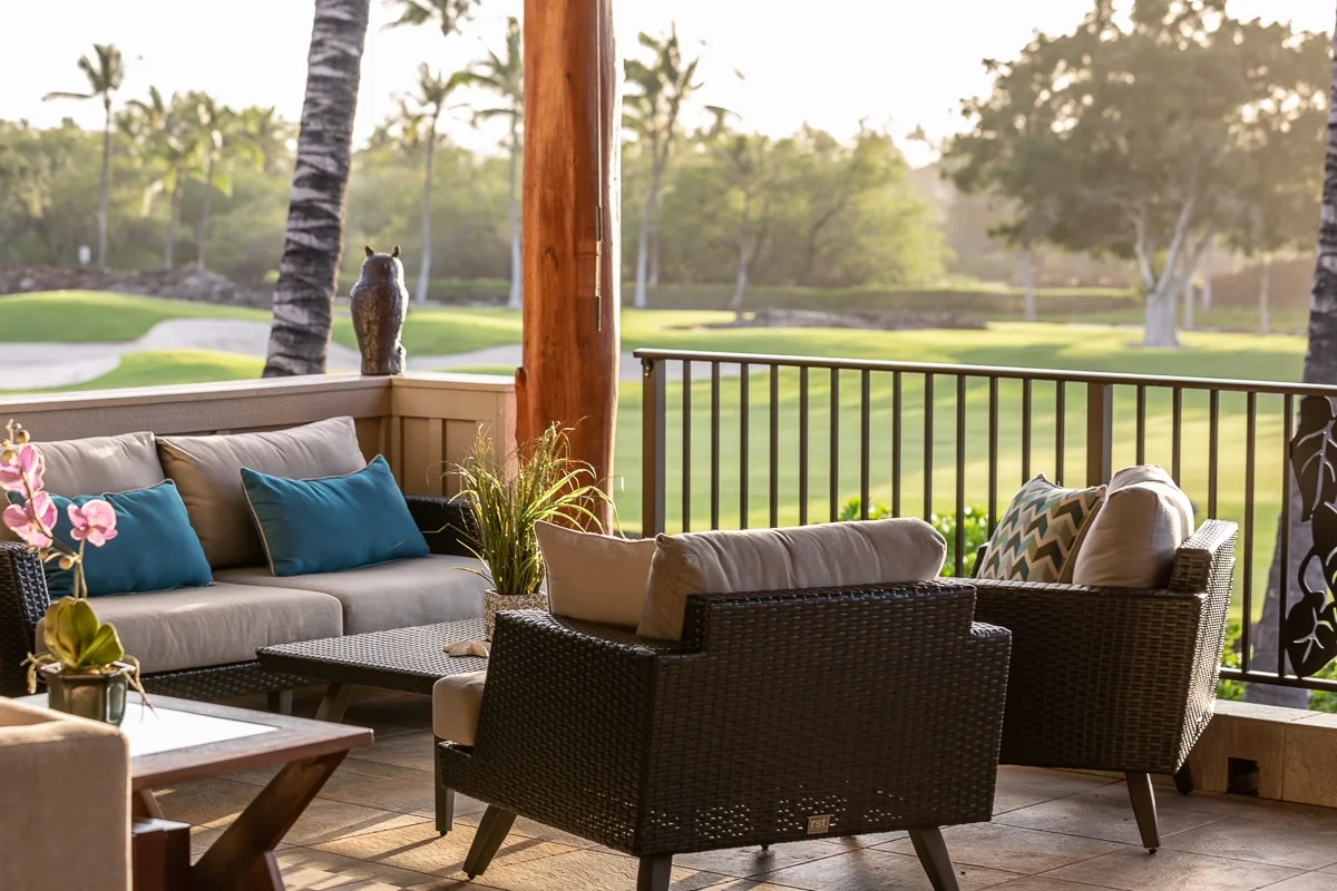 An outdoor patio seating area overlooks a green lawn and trees.