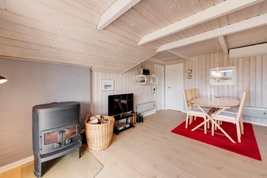 Una sala revestida de madera con estufa, televisor y mesa de comedor.