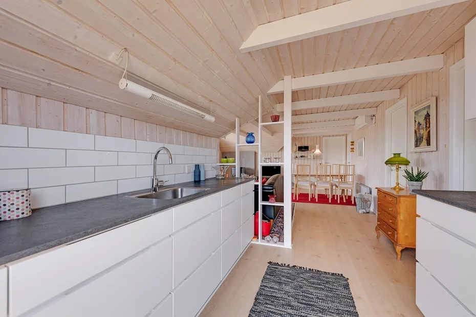 Una cocina luminosa con una encimera larga y una mesa de comedor al fondo.