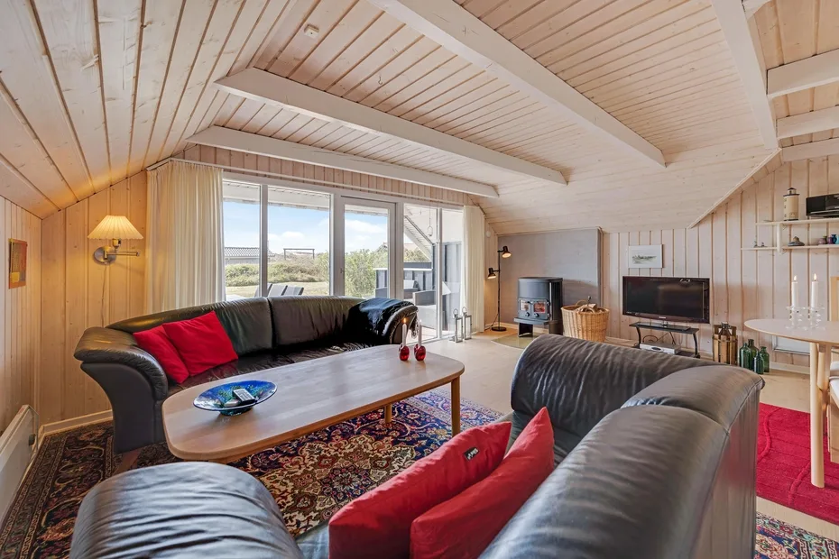 Una sala luminosa con asientos, una mesa de centro y ventanas grandes.