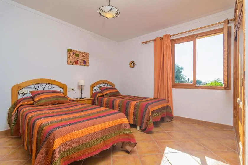 Un dormitorio con dos camas cubiertas con ropa de cama a rayas coloridas y una ventana.