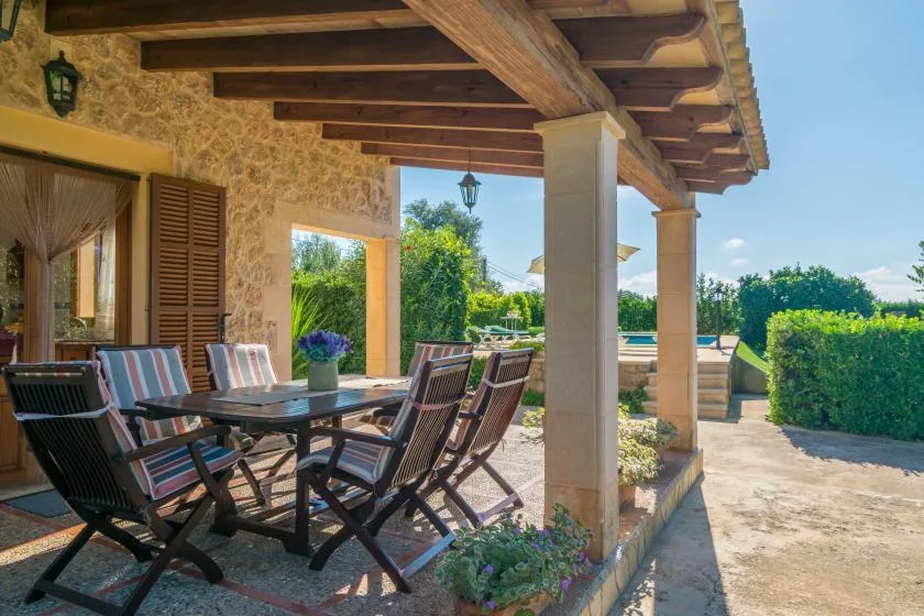 Una zona cubierta para comer al aire libre da a un jardín y una piscina.
