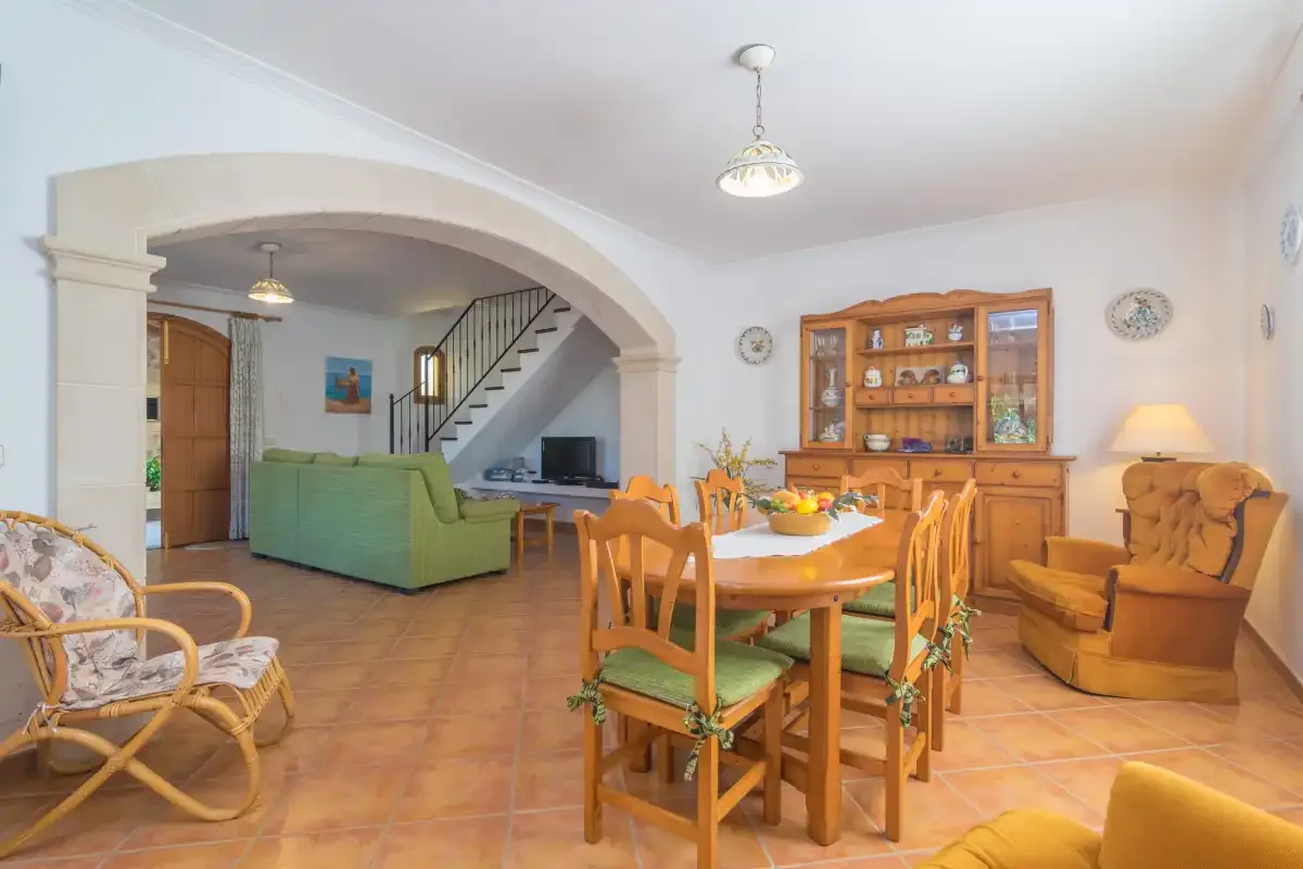 Un comedor y sala de estar con una mesa de madera y asientos verdes.