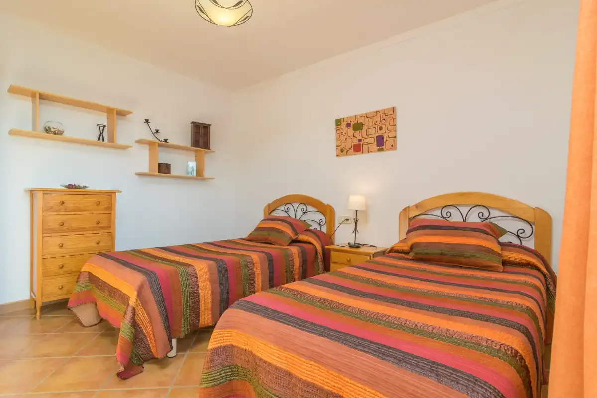 Un dormitorio con dos camas cubiertas con ropa de cama de rayas coloridas.