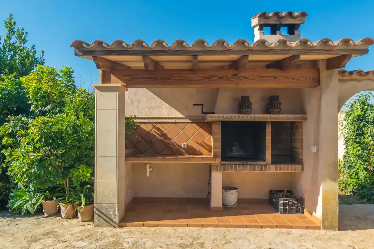 Una zona de cocina exterior cubierta con parrilla empotrada y encimera de azulejos.