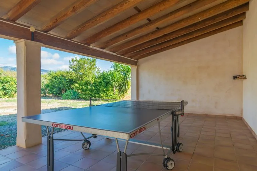 Un patio cubierto con una mesa de ping-pong y una vista abierta de vegetación.