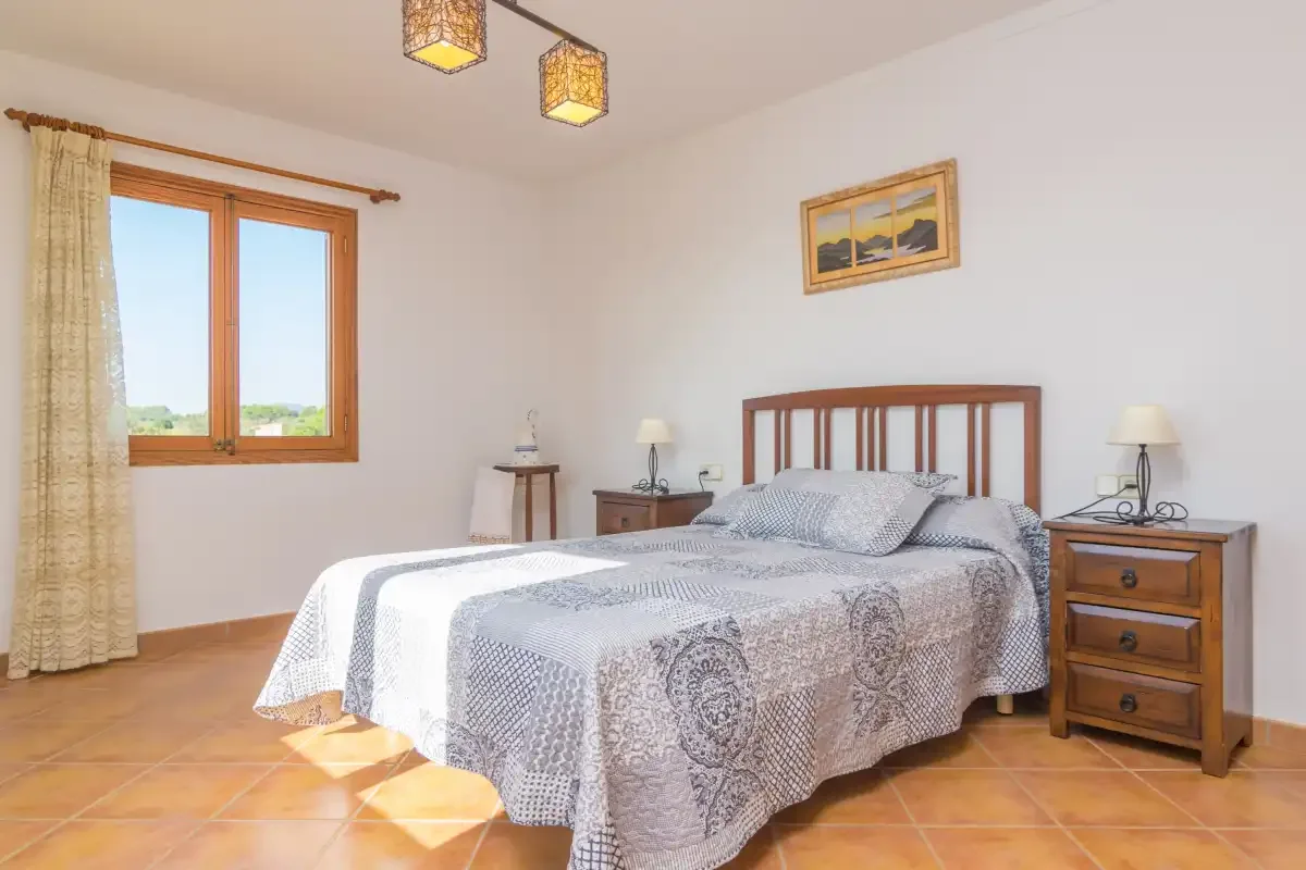 Un dormitorio con una cama doble, mesitas de madera y una ventana.