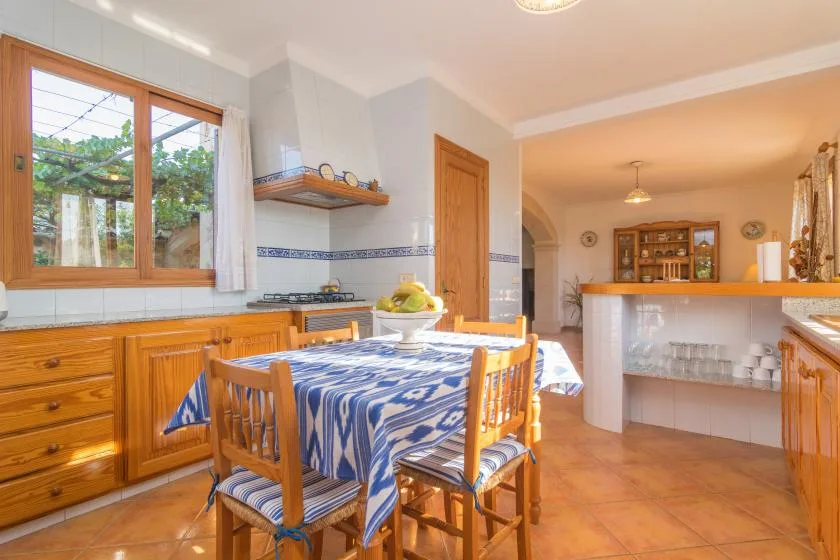 Un comedor con un mantel estampado y asientos de madera junto a una ventana.