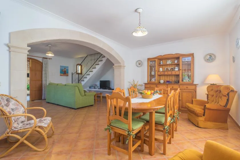Un comedor y sala de estar con una mesa de madera bajo un amplio arco.