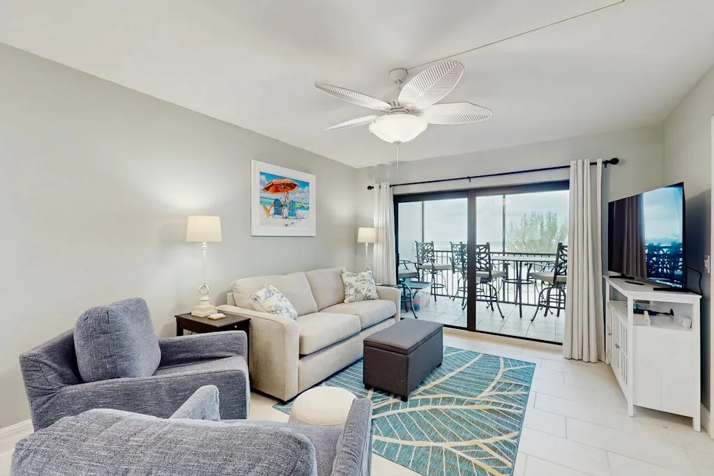 A living room with seating, a coffee table, and sliding glass doors opening to a balcony.
